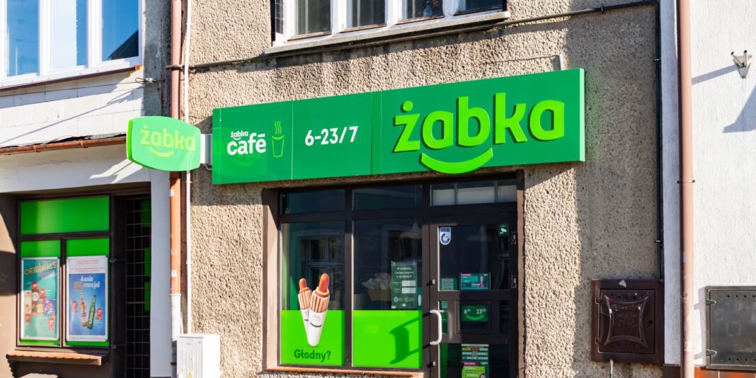 Магазин мережі Żabka у Польщі з фірмовою зеленою вивіскою та входом до торгової точки.