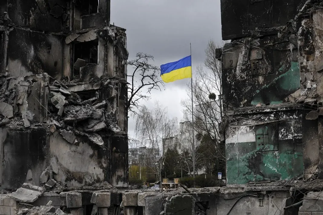 Зруйновані будинки в Україні через війну та український прапор між руїнами.