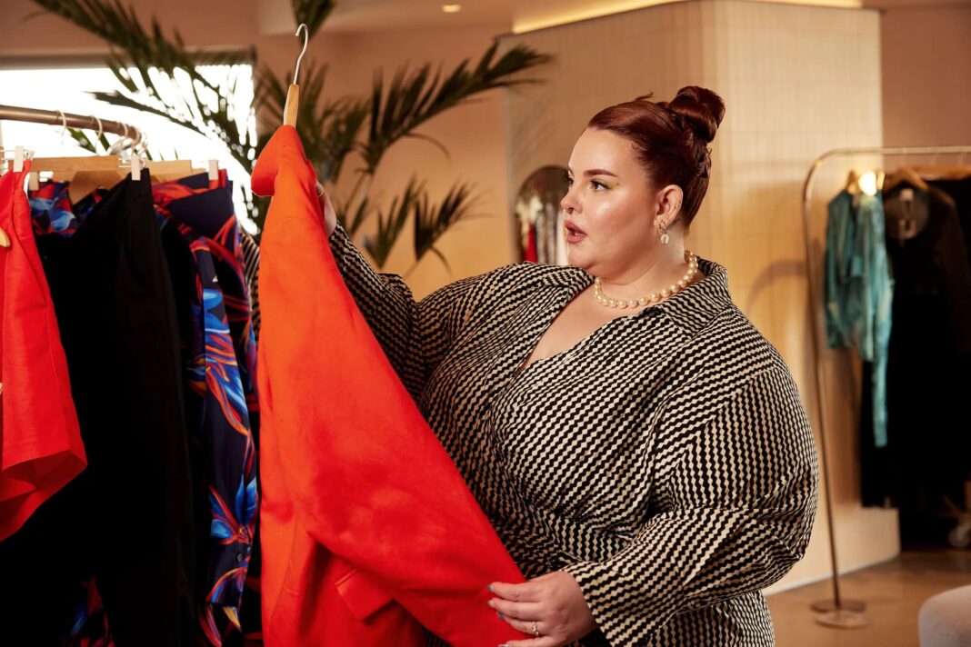 Plus-size модель Тесс Голлідей вибирає одяг у шоурумі.
