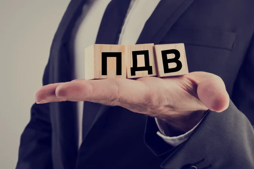 Людина в костюмі тримає на долоні кубики з написом ПДВ
